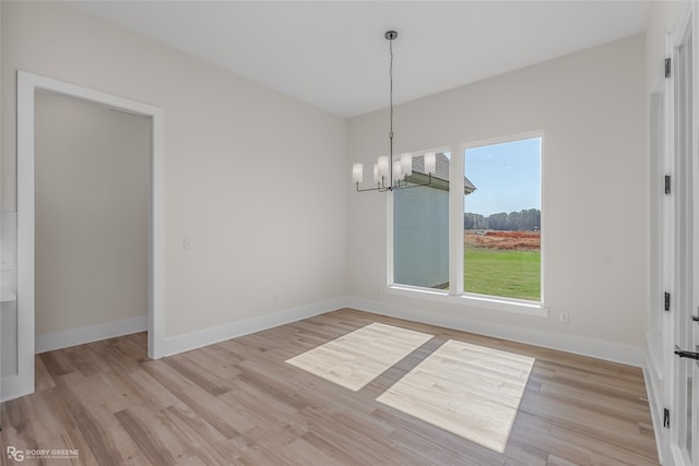 unfurnished dining area featuring light wood-type flooring and a chandelier