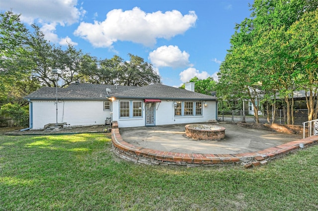 back of property with a fire pit, a chimney, fence, a yard, and a patio area