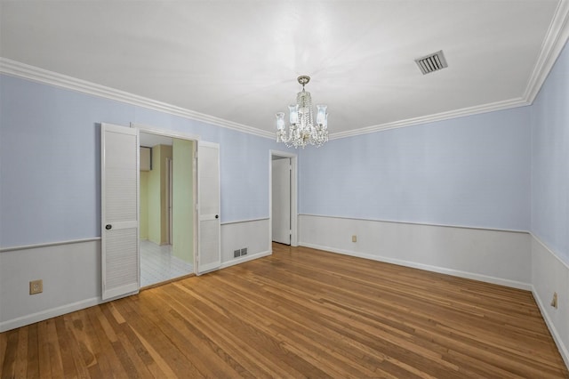 unfurnished room featuring a chandelier, hardwood / wood-style flooring, and crown molding