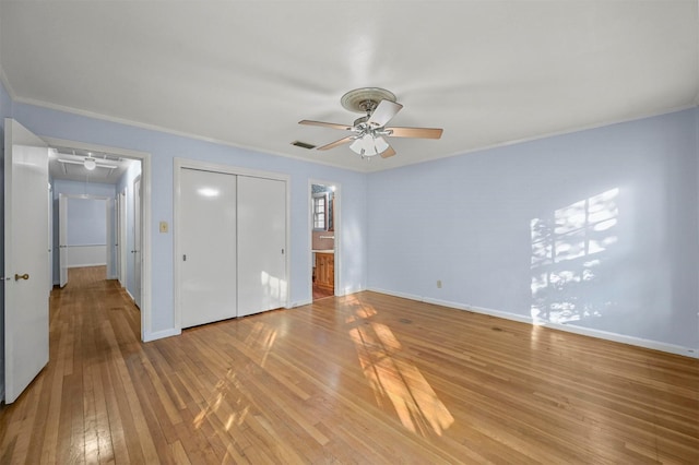 unfurnished bedroom featuring connected bathroom, ceiling fan, light hardwood / wood-style flooring, crown molding, and a closet