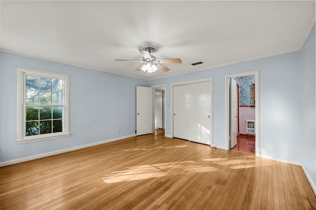 unfurnished bedroom featuring ceiling fan, light wood-type flooring, and heating unit