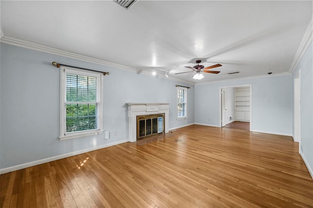 unfurnished living room featuring ceiling fan, ornamental molding, a healthy amount of sunlight, and light wood-type flooring