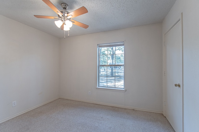 spare room with ceiling fan, light colored carpet, and a textured ceiling