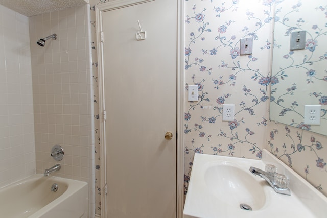 bathroom with vanity, tiled shower / bath combo, and a textured ceiling