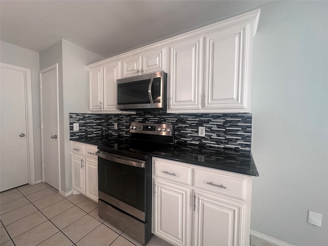 kitchen featuring stainless steel appliances, light tile patterned flooring, white cabinets, and decorative backsplash