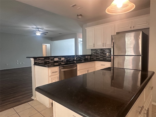 kitchen with stainless steel appliances, backsplash, light wood-type flooring, and white cabinetry