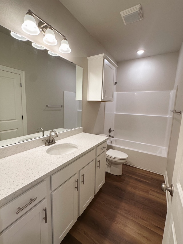 bathroom with visible vents, toilet, wood finished floors, vanity, and shower / washtub combination