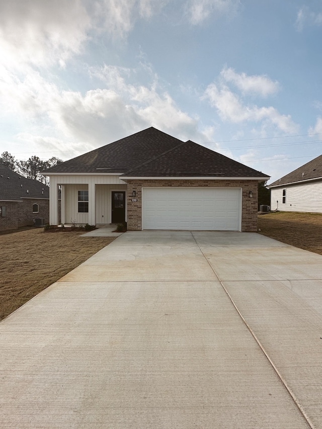 ranch-style house with brick siding, a shingled roof, an attached garage, board and batten siding, and driveway