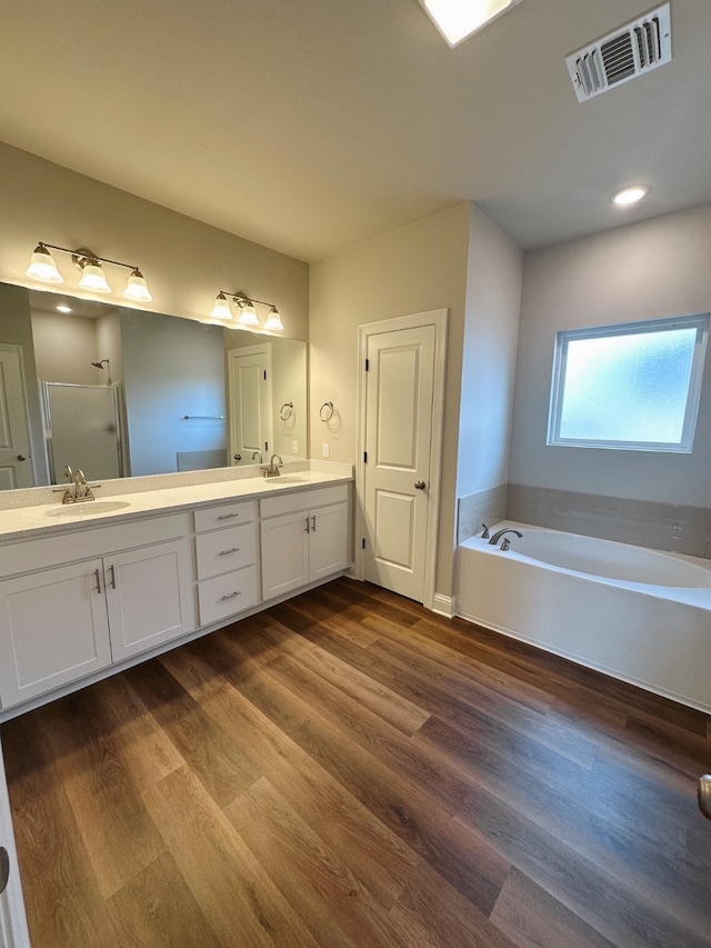 bathroom with visible vents, a sink, a garden tub, and wood finished floors