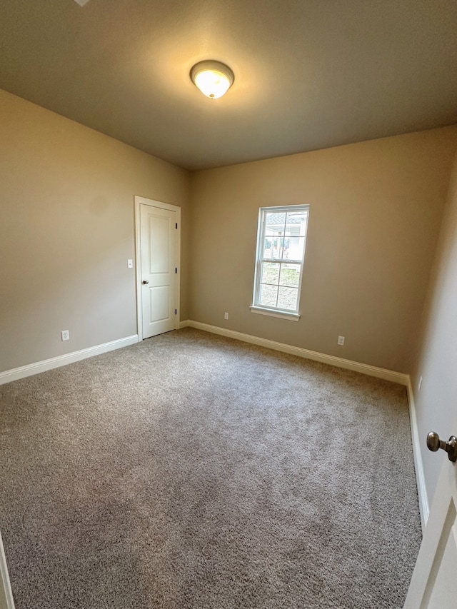 carpeted spare room featuring baseboards