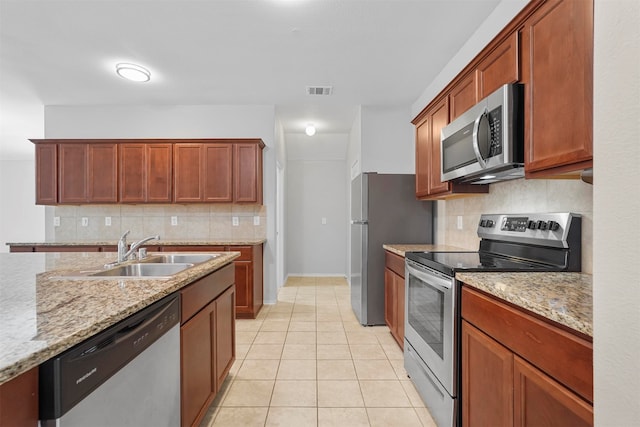 kitchen featuring light tile patterned flooring, sink, stainless steel appliances, light stone countertops, and decorative backsplash