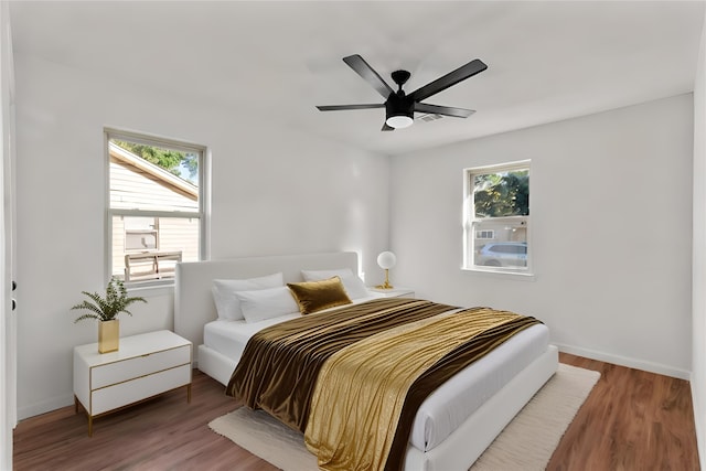 bedroom with hardwood / wood-style flooring, ceiling fan, and multiple windows