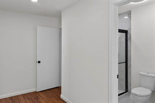 interior space featuring wood-type flooring, toilet, and a shower with door