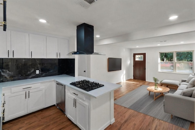 kitchen with white cabinetry, black gas stovetop, wall chimney range hood, and hardwood / wood-style flooring