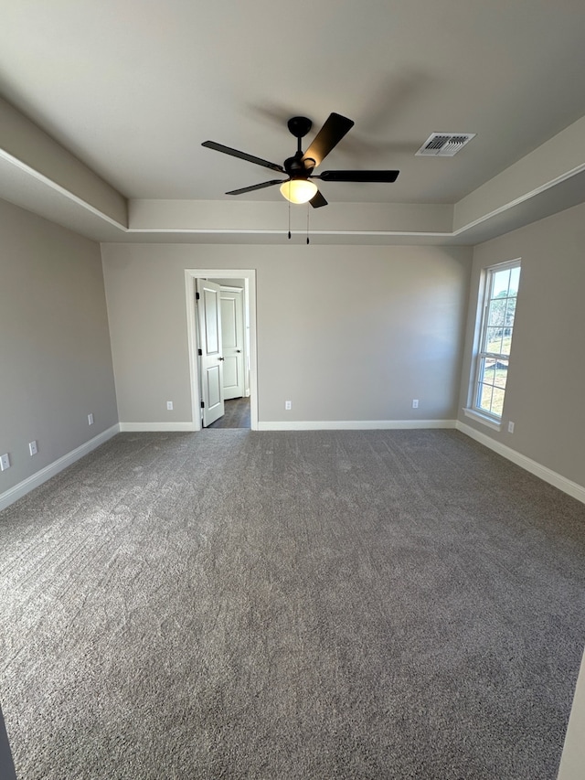 carpeted spare room with a tray ceiling and ceiling fan