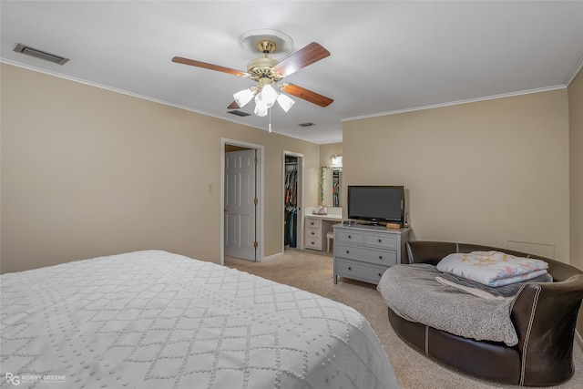 carpeted bedroom featuring ceiling fan, ensuite bathroom, ornamental molding, and a walk in closet