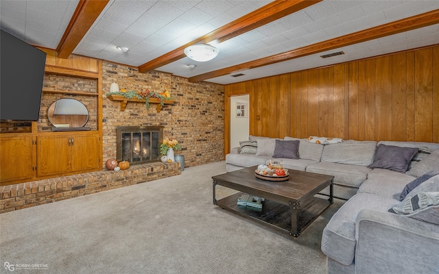 living room featuring a brick fireplace, beamed ceiling, wooden walls, and light carpet