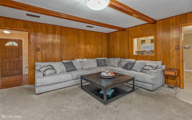 living room with light carpet, beamed ceiling, and wooden walls