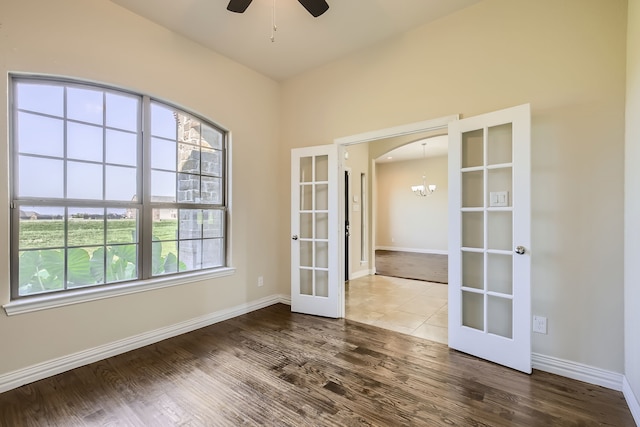 unfurnished room featuring ceiling fan with notable chandelier, french doors, and wood-type flooring