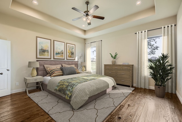 bedroom with ceiling fan, wood-type flooring, and a raised ceiling