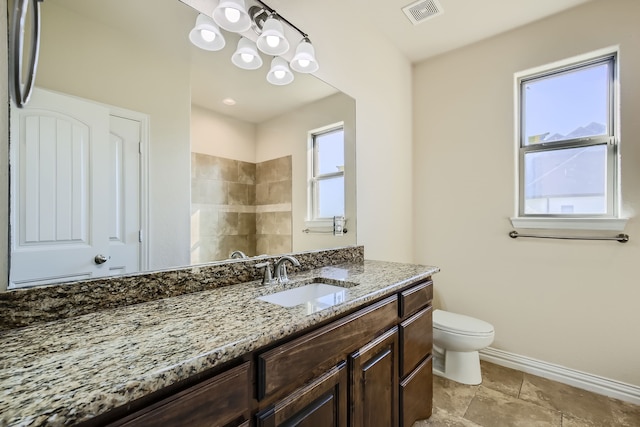 bathroom featuring a healthy amount of sunlight, vanity, toilet, and a shower