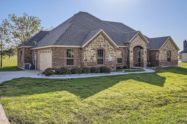 french country inspired facade featuring a garage, a front yard, and central AC unit