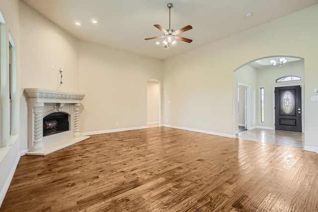 unfurnished living room featuring ceiling fan with notable chandelier and hardwood / wood-style flooring