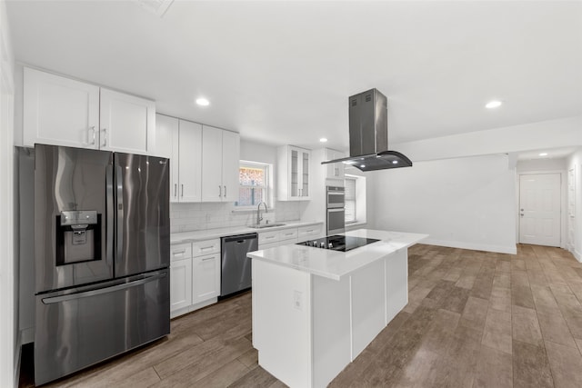 kitchen featuring island exhaust hood, stainless steel appliances, white cabinets, light hardwood / wood-style floors, and a kitchen island