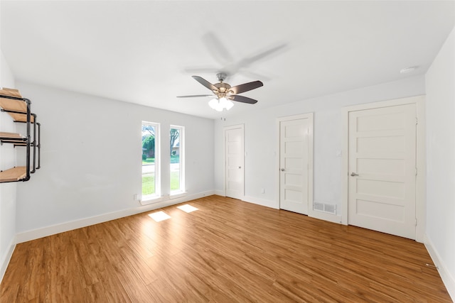 unfurnished bedroom with two closets, light hardwood / wood-style floors, and ceiling fan