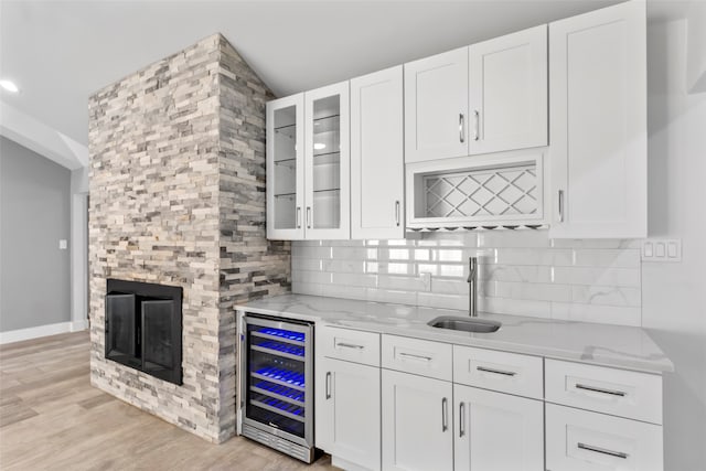 kitchen featuring white cabinets, light stone counters, beverage cooler, and light hardwood / wood-style flooring