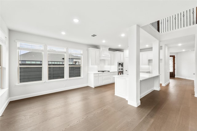 kitchen featuring a center island, custom range hood, white cabinets, and hardwood / wood-style floors