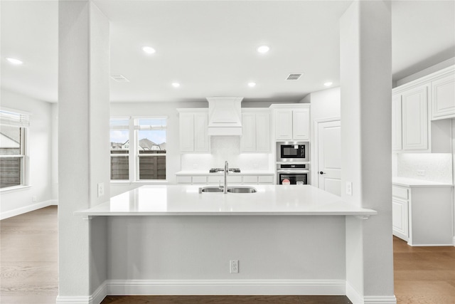 kitchen with oven, custom range hood, and white cabinets