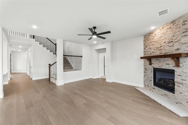 unfurnished living room with a fireplace, ceiling fan, and light wood-type flooring