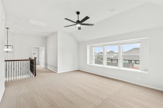 carpeted empty room with vaulted ceiling and ceiling fan with notable chandelier