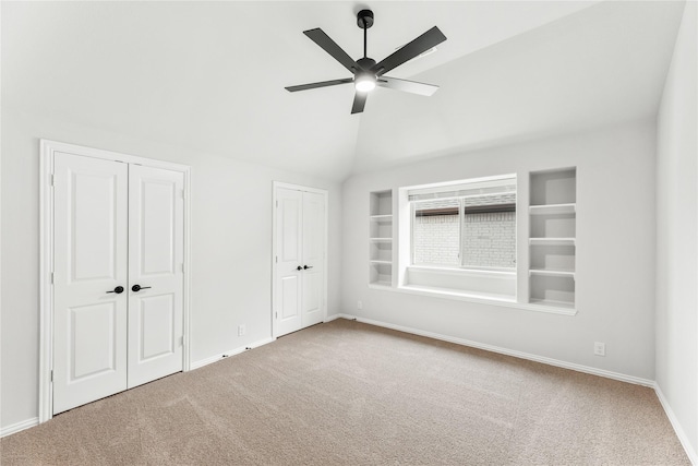 unfurnished bedroom featuring vaulted ceiling, ceiling fan, carpet floors, and two closets