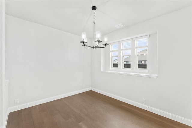 spare room with hardwood / wood-style floors and a notable chandelier