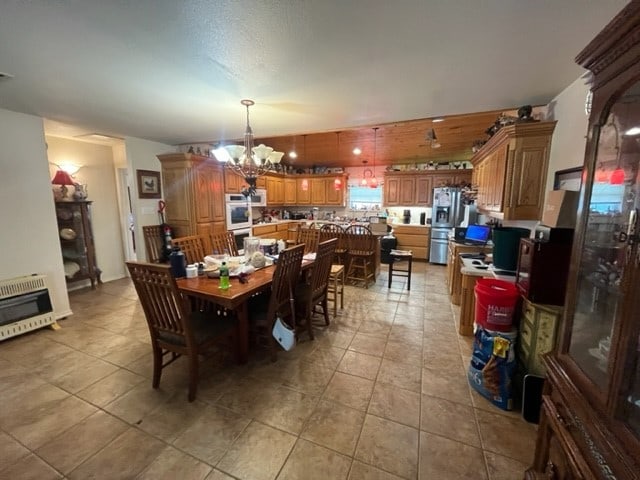 dining area with light tile patterned flooring, heating unit, and an inviting chandelier