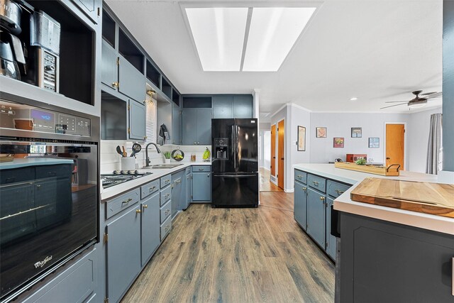 kitchen with open shelves, a sink, black appliances, wood finished floors, and a ceiling fan