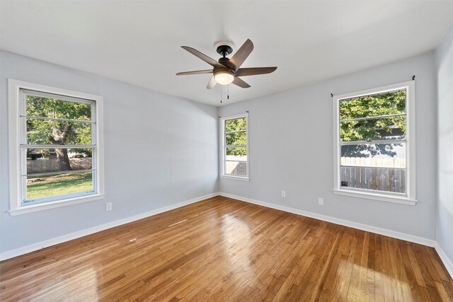 empty room featuring hardwood / wood-style flooring, a ceiling fan, and baseboards