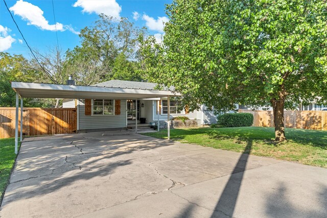 view of front of house with fence, a carport, driveway, and a front lawn