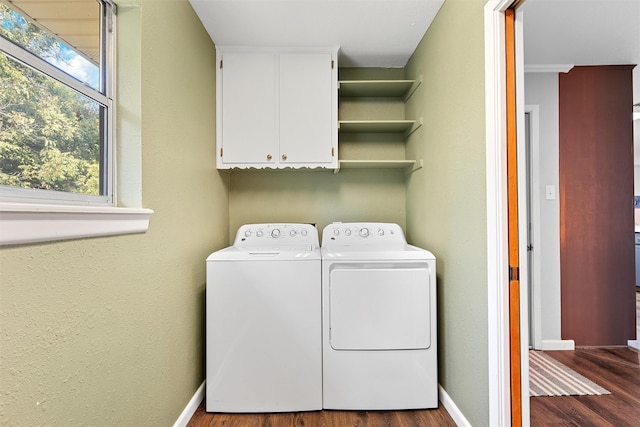 clothes washing area featuring dark wood-style floors, baseboards, separate washer and dryer, and cabinet space