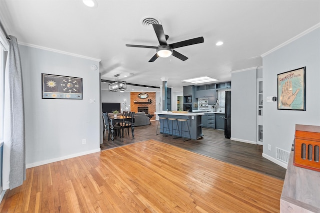 kitchen featuring light countertops, ornamental molding, ceiling fan, visible vents, and open floor plan