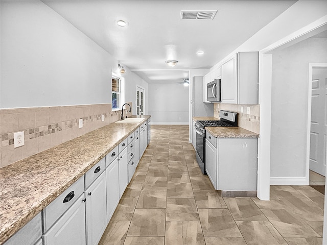 kitchen with appliances with stainless steel finishes, white cabinetry, sink, and backsplash