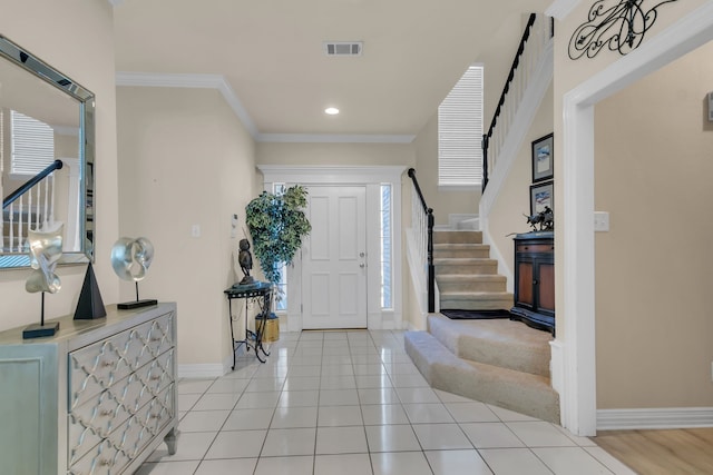 entryway featuring crown molding, a wealth of natural light, and light tile patterned floors