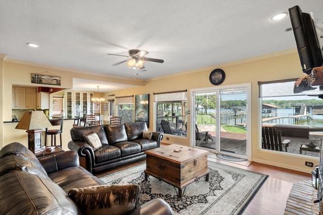 living room featuring crown molding, ceiling fan with notable chandelier, a textured ceiling, and hardwood / wood-style flooring