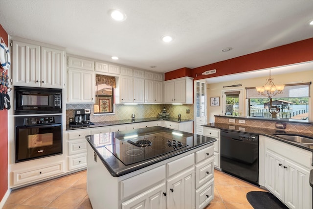 kitchen with white cabinetry, a center island, light tile patterned floors, a notable chandelier, and black appliances