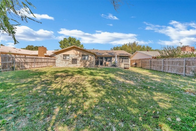 back of property featuring a fenced backyard, a lawn, and brick siding