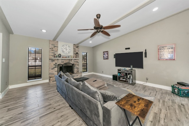 living room with a large fireplace, light hardwood / wood-style floors, a wealth of natural light, and ceiling fan