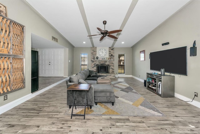 living room featuring a brick fireplace, light hardwood / wood-style flooring, vaulted ceiling, plenty of natural light, and ceiling fan