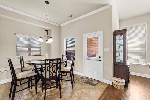 dining area with ornamental molding, hardwood / wood-style floors, and an inviting chandelier